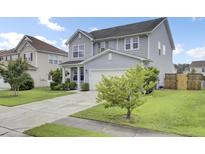 Charming two-story home featuring a well-manicured lawn and a long driveway leading to an attached garage at 145 Woodbrook Way, Moncks Corner, SC 29461