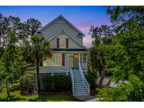 Charming home featuring a welcoming front porch and neatly landscaped yard with mature trees and colorful red window shutters at 2301 N Creek Dr, Mount Pleasant, SC 29466