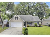 Charming single-story home with a manicured lawn, attached garage, and mature trees at 8612 Hickory Creek Ln, North Charleston, SC 29420