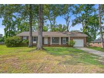 Charming single-story brick home featuring a manicured lawn, mature trees, and a cozy front porch at 127 Cornell Dr, Ladson, SC 29456