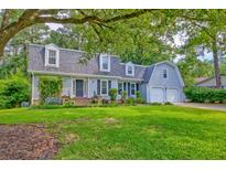 Charming home with dormer windows, attached garage, lush landscaping, and a bench in front at 202 Hunt Club Dr, Summerville, SC 29485