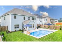 Backyard view of pool with patio furniture and well-maintained lawn at 256 Fiddleback Dr, Summerville, SC 29486