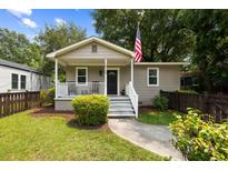 Charming home featuring a covered porch, freshly painted siding, manicured lawn and a quaint American flag at 2924 Alabama Dr, North Charleston, SC 29405