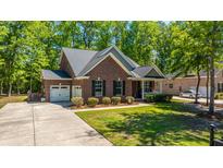 Charming brick home with a well-manicured lawn, attached garage, and a cozy front porch, nestled among mature trees at 5442 Clearview Dr, North Charleston, SC 29420