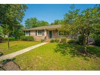 Charming brick home featuring a well-manicured lawn and mature trees on a sunny day at 100 S Gum St, Summerville, SC 29483