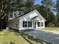 Charming new construction home with a white exterior, black shutters, and a gravel driveway at 110A Dukes St, Saint George, SC 29477