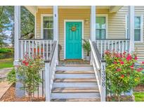 Charming home entrance featuring a bright teal door with a wreath and beautiful flower bushes at 1338 Addykay Pl, North Charleston, SC 29406