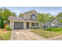 Charming two-story home featuring a cozy front porch, attached garage, and well-maintained lawn at 1743 Orange Grove Shores Dr, Charleston, SC 29407