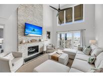 Bright living room features a fireplace, modern ceiling fan, and balcony with marina views at 1948 Marsh Oak Ln, Seabrook Island, SC 29455