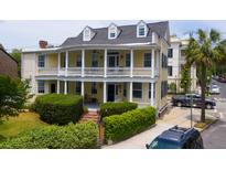 Charming yellow two-story home featuring a double veranda and manicured landscaping at 29 Smith St, Charleston, SC 29401