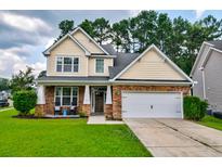 Charming two-story home featuring a manicured lawn, stone accents, and an attached two-car garage at 314 Freeland Way, Moncks Corner, SC 29461