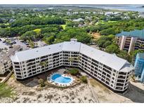 Stunning aerial view of the condo building, pool and lush green surroundings with beach access and partial ocean views at 9002 Palmetto Dr # 420, Isle of Palms, SC 29451