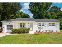 Charming white brick home featuring shutters, manicured lawn and mature trees at 1107 S Shadow Dr, Mount Pleasant, SC 29464
