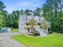 Charming two-story home with a metal roof, double porches, mature trees, and lush landscaping at 142 Maxwell Rd, Summerville, SC 29483