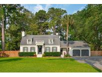 Charming home with a manicured lawn, dark shutters, and a brick paver driveway leading to the attached garage at 1446 Burningtree Rd, Charleston, SC 29412