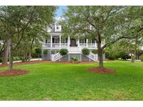 Charming two-story home with large, inviting front porch, lush green lawn and beautiful mature trees at 2293 Beckenham Dr, Mount Pleasant, SC 29466