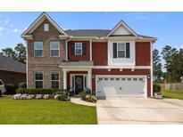 Inviting two-story home featuring brick and red siding, attached two-car garage, and manicured lawn at 255 Saxony Loop, Summerville, SC 29486