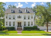 Charming two-story home features a landscaped yard, brick stairs, and inviting front entryway with traditional-style shutters at 27 Watroo Pt, Daniel Island, SC 29492