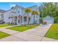 Charming two-story home with light blue siding, a manicured lawn, palm trees, and a long driveway at 2710 Mcfadden Way, Johns Island, SC 29455
