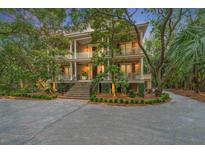 Elegant three-story home with a brick staircase leading to a welcoming front porch surrounded by lush greenery at 43 Surfsong Rd, Kiawah Island, SC 29455