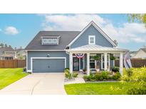 Charming home featuring a covered porch, gray siding, a well-manicured lawn, and an attached two-car garage at 627 Macintyre Cir, Summerville, SC 29486