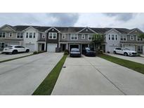 View of townhomes with individual garages and driveways, with tasteful neutral exterior colors, and well-manicured landscaping at 9712 Transplanter Cir, Ladson, SC 29456