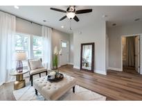 Bright living room featuring wood floors, a ceiling fan, and a large window with white curtains at St, Saint George, SC 29477