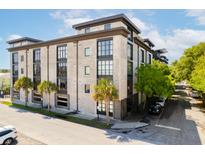 Modern condo building with concrete facade, large windows, and palm trees in Charleston, SC at 1 Cool Blow St # 124, Charleston, SC 29403