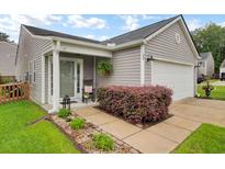 Charming single-story home with gray siding, well-manicured landscaping, and a welcoming front porch at 100 Runnels Cv, Summerville, SC 29485