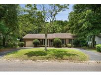 Charming brick home featuring a well-manicured lawn, mature tree, and a welcoming front porch at 1002 Sea Gull Dr, Mount Pleasant, SC 29464