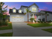Charming two-story home with a manicured lawn, covered porch, and attached two-car garage at dusk at 111 Medford St, Summerville, SC 29486