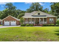 Charming brick home boasts a welcoming front porch, lush lawn, and detached two-car garage at 1119 Bruton Blvd, Moncks Corner, SC 29461