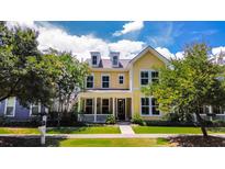 Charming two-story yellow home with dormer windows and a welcoming front porch at 157 Village Ponds Dr, Summerville, SC 29483