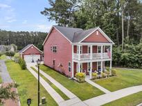 Charming red two-story home with a double porch, well-manicured lawn, and detached garage at 1576 Nautical Chart Dr, Charleston, SC 29414