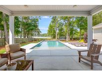 Stunning pool view surrounded by lush trees and lake, seen from covered outdoor living space at 1607 Waterside Blvd, Moncks Corner, SC 29461