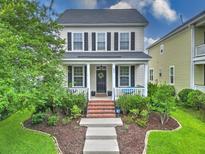 Charming two-story home featuring a cozy front porch, manicured lawn, and a welcoming landscaped yard at 205 White Gables Dr, Summerville, SC 29483