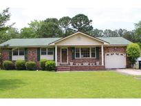 Charming single-story brick home with green roof, lush lawn, and attached garage at 2163 Pinehurst Ave, Charleston, SC 29414