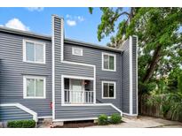 Charming gray two-story home with a small porch and lush green landscaping under a blue sky at 22 Ogier St, Charleston, SC 29403