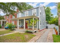 Charming two-story home with a inviting front porch and brick walkway, set against a backdrop of lush greenery at 293 Grove St, Charleston, SC 29403