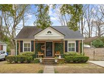 Charming brick home featuring black shutters, mature landscaping, and inviting front porch with seating at 38 Colleton Dr, Charleston, SC 29407