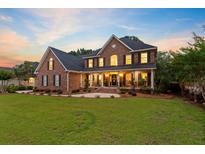 Beautiful two-story brick home featuring a covered front porch, well-manicured lawn, and professional landscaping at 4246 Club Course Dr, North Charleston, SC 29420