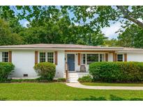 Charming white brick home featuring a cozy front porch with a blue door and well-maintained landscaping at 4939 Ashby Ave, North Charleston, SC 29405