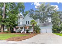 Charming two-story home boasts a welcoming front porch, mature trees, and a well-manicured lawn at 111 Long Bow Rd, Summerville, SC 29485