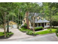 Charming two-story yellow home with a brick chimney, attached garage and a wraparound front porch at 127 White Pine Way, Summerville, SC 29485