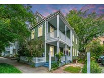 Charming two-story home with double porches and white picket fence, surrounded by lush greenery at 173 Fishburne St, Charleston, SC 29403