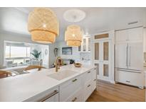 Bright kitchen with white cabinets, brass hardware, and rattan pendant lighting and an island with a breakfast bar at 1815 Long Bend Dr, Seabrook Island, SC 29455