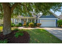 Charming home featuring a manicured front lawn, tree, and a welcoming facade with covered porch and attached garage at 185 Red Leaf Blvd, Moncks Corner, SC 29461