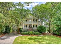 Stunning two-story home with double porches, lush landscaping, and a charming, tree-lined driveway at 392 Tombee Ct, Mount Pleasant, SC 29464