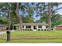 Charming white brick home featuring black shutters and door, manicured landscaping, and a covered parking area at 403 Wedgewood St, Charleston, SC 29407