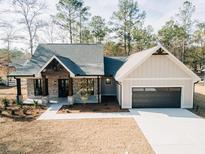 Charming single-story home showcasing a brick and siding exterior with a dark gray garage door and inviting front porch at 54 Summer Dr, Walterboro, SC 29488